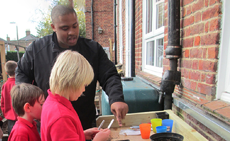 Student working with two school children in England