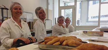 Students in chef's jackets and hair nets while making bread in Montpellier, France.